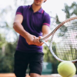 Young man tennis player at the court, tennis racket close up